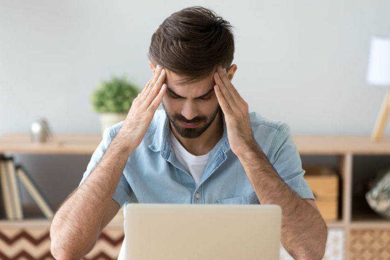 man with headache at work | take a break from trading