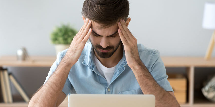 man with headache at work | take a break from trading