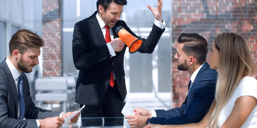 boss screams on the business team through a megaphone ignore the market doomsayers | businessman talking through a megaphone