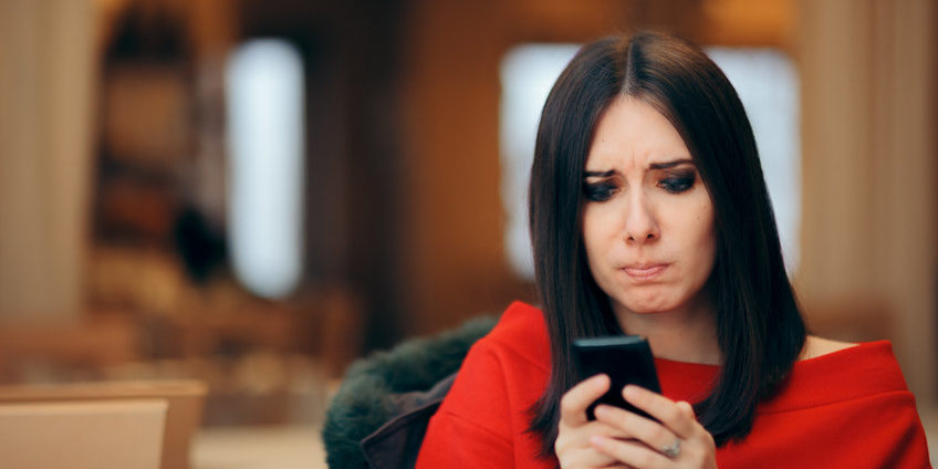 Stressed Woman Reading Text Message on Smartphone ignore fear of missing out | woman feeling stressed while looking at her smartphone