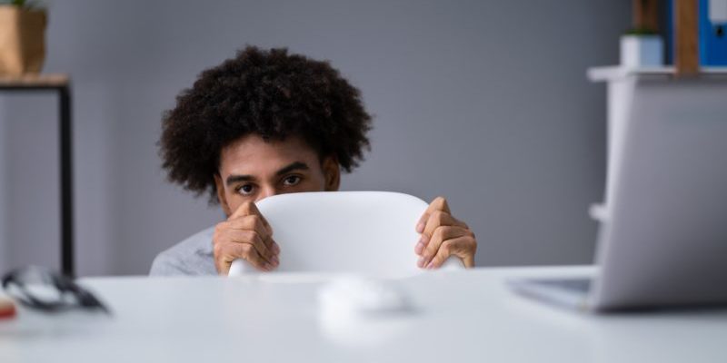 scared trader hiding behind his chair | fear of loss