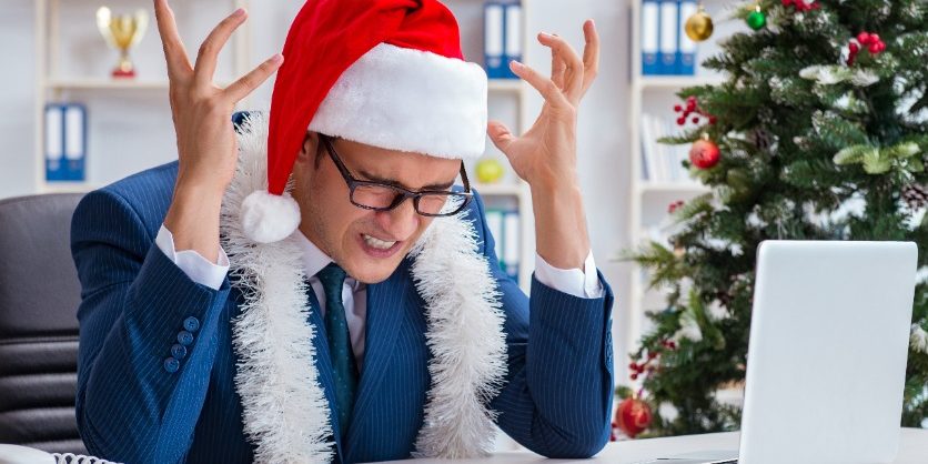 Businessman celebrating christmas holiday in the office business person in Santa hat | seasonal trends