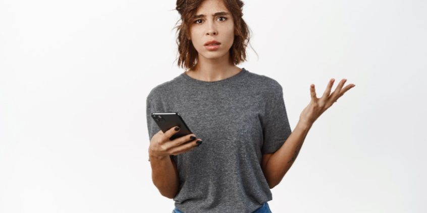 shrugging woman holding smartphone | price and volatility