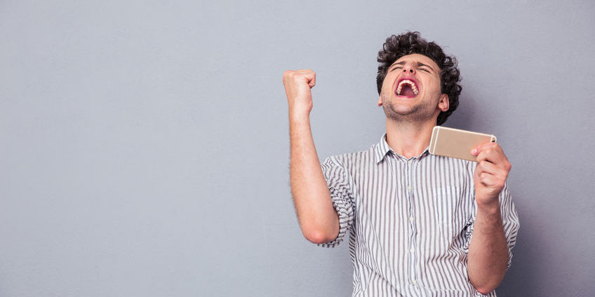 Man holding smartphone and celebrating his success big options trade winner