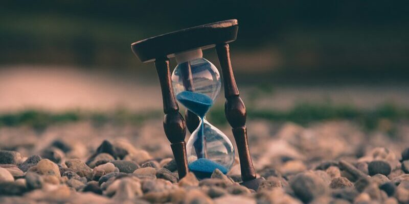 time investing | hour glass sitting on rocks