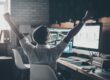 trader at desk raising arms in victory | bullish stock market signal