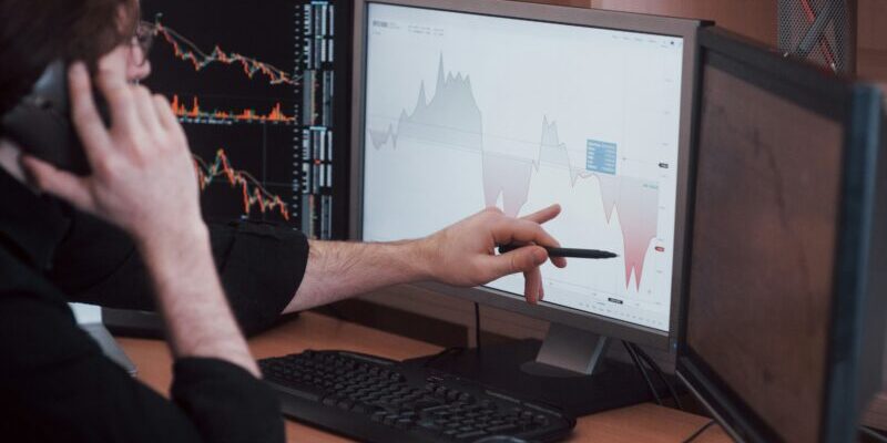 trader discussing bearish chart | rising market volatility is dangerous