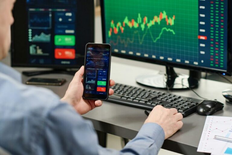 man trading using moible phone and multiple screens | best indicators for day trading