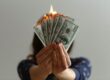 woman holding money that is burning | bad stock market news