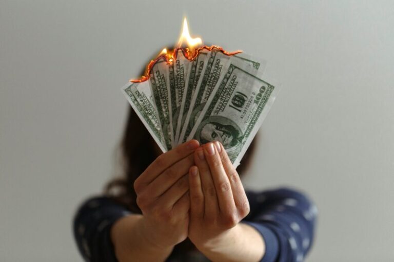 woman holding money that is burning | bad stock market news