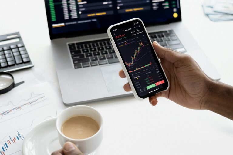 trader holding phone and cup of coffee | options trading success tips