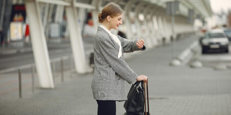 business woman with luggage checking the time | sell in May and go away