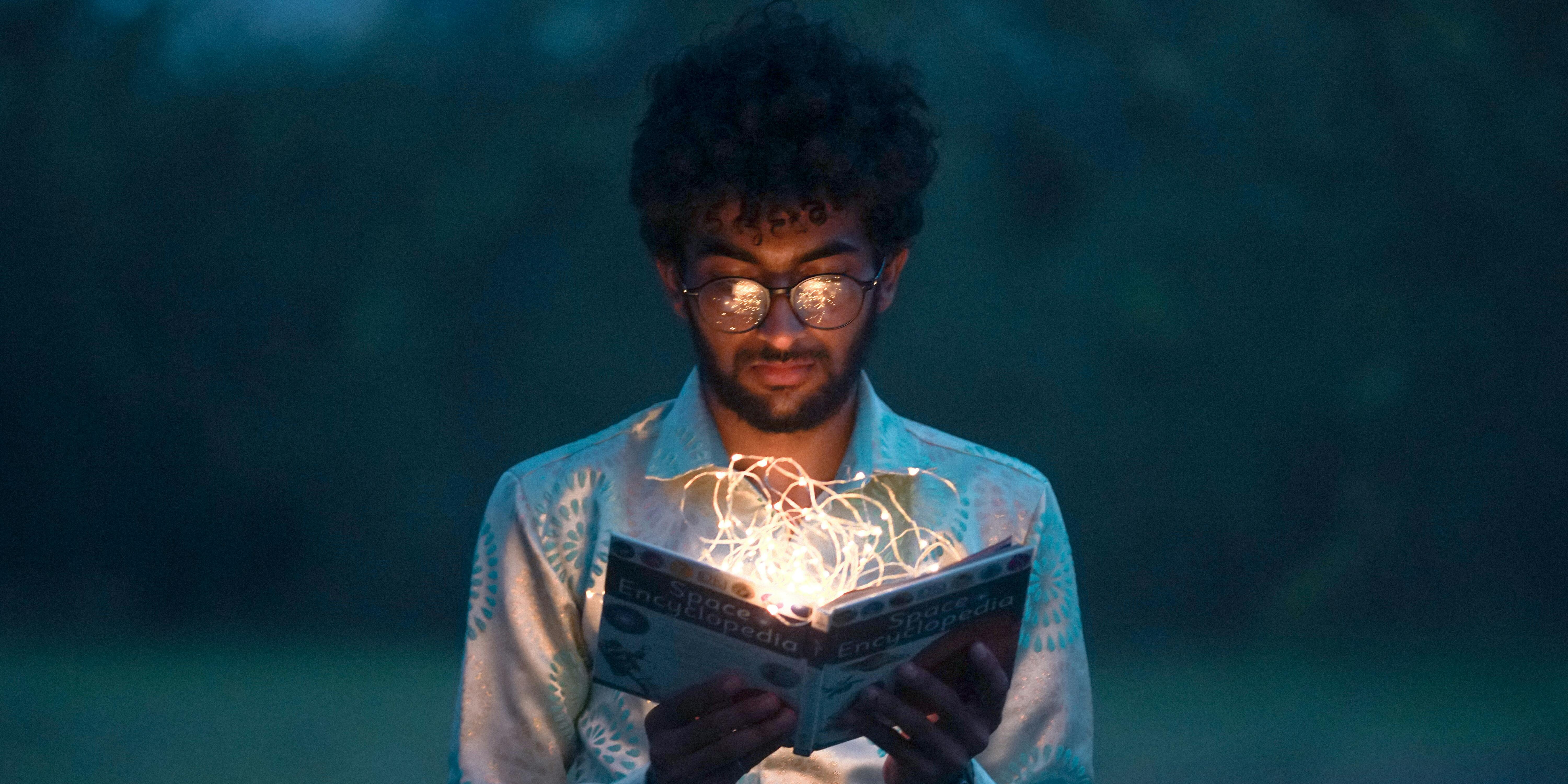 man reading a book with fairy lights in it | tips to improve trading performance